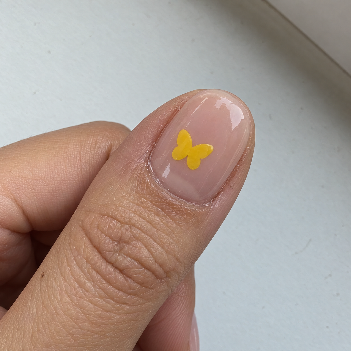 Yellow butterfly HerSafe sticker on a gel nail
